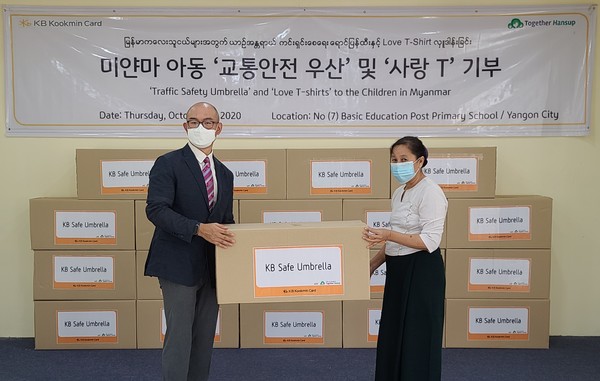 ▲지난 22일 이익수 KB국민카드 미얀마 양곤 대표 사무소장(왼쪽)이 도 흘라라(DAW HLA HLA) 7번 학교 교무 교사에게 기부 물품을 전달하고 있다.