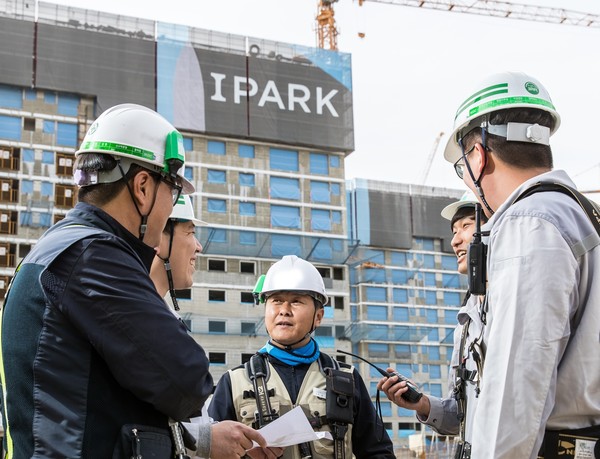 HDC현대산업개발 직원과 협력사 직원들이 IPARK 현장에서 대화를 나누고 있다