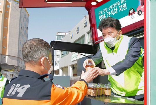 ▲ 함영주 회장(사진 오른쪽)이 울진소방서에 지원한 간식 차량에 직접 올라 타 소방대원에게 커피를 전달하고 있다.