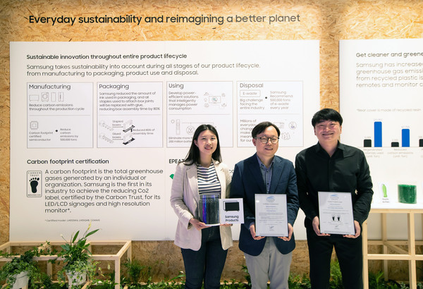 ▲ISE 2022가 열리고 있는 스페인 바르셀로나 피라 그라 비아 전시장에서 삼성전자 영상디스플레이사업부 Enterprise 개발 이종포 상무(가운데)와 개발자들이 사이니지 제품 탄소 발자국 인증서와 제품에 활용되는 재생 플라스틱을 들고 있다. 