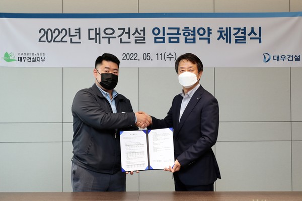 ▲ 백정완 대우건설 대표(오른쪽)와 심상철 노동조합 위원장이 임금협약서를 들고 악수하고 있다.
