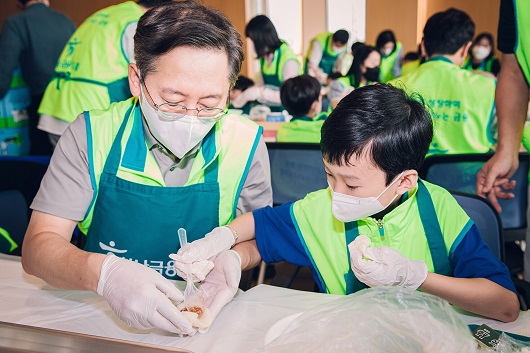 ▲ 봉사활동에 참여한 박성호 하나은행장(사진 왼쪽)이 직원 자녀와 함께 청라 인근 재래시장에서 직접 구입한 송편 재료로 송편을 빚고 있다.