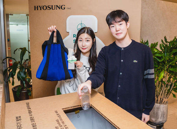효성티앤씨 직원들이 페트병 수거함 앞에서 리젠 적용 가방과 재활용할 페트병을 들고 있다.