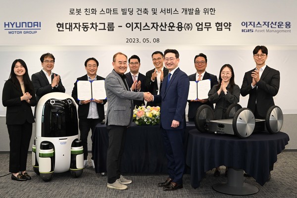 ▲현대차∙기아의 실내외 배송 로봇(왼쪽)과 모베드(MobED, 오른쪽)가 놓인 가운데 현대차∙기아 연구개발본부장 김용화 부사장(앞줄 왼쪽)과 이지스자산운용 리얼에셋부문 정석우 대표(앞줄 오른쪽)가 기념 사진을 촬영하고 있다.