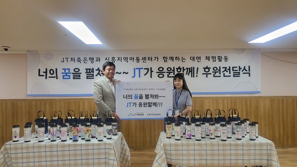 ▲강재훈 JT저축은행 커뮤니케이션본부 차장이 이상영 신흥아동복지센터 센터장에게 후원금과 임직원이 제작한 친환경 텀블러를 전달하고 있다.