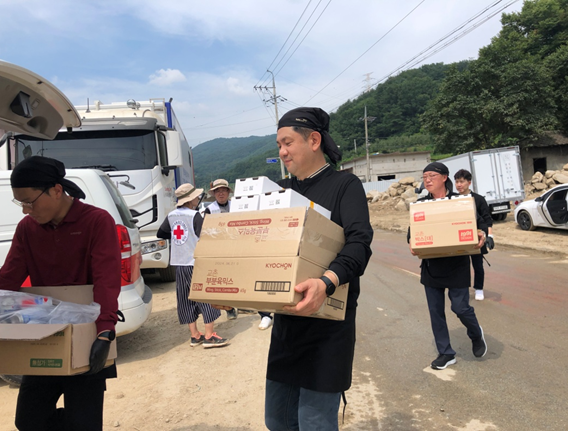 ▲교촌에프앤비 임직원 봉사단과 교촌치킨 가맹점주들이 경상북도 예천군 감천면 수해현장에 방문해 치킨 나눔 활동을 진행하고 있다.