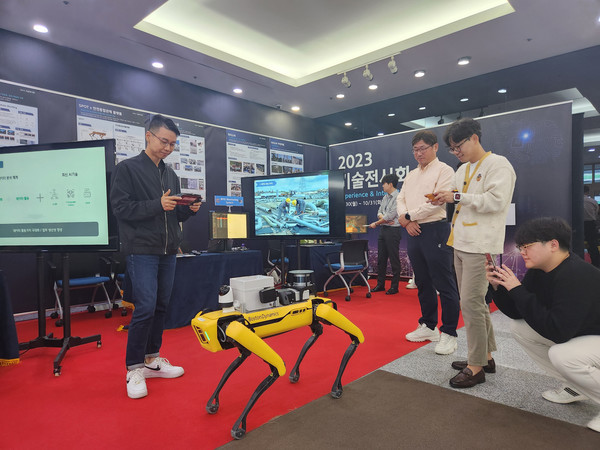 ▲ 현대엔지니어링 본사 1층에서 진행중인 ‘2023 스마트 건설 기술 전시회’에 참가한 사람들이 4족 보행 순찰로봇 ‘스팟(SPOT)’을 구경하고 있다.