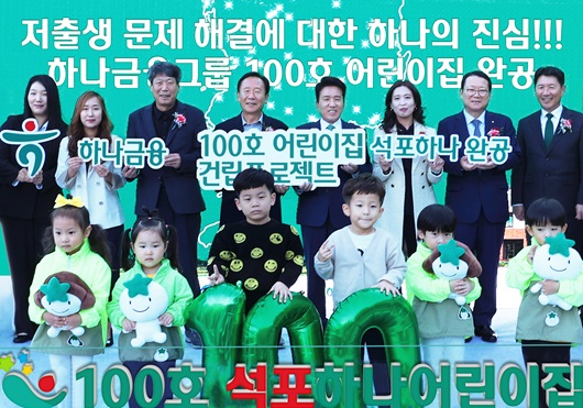 ▲ 지난 10월 31일에 열린 개원식에 참석한 함영주 하나금융그룹 회장(사진 뒷줄 왼쪽에서 다섯번째)과 박현국 봉화군수(사진 뒷줄 왼쪽에서 네번째)가 어린이집 원장, 학부모, 어린이, 지역주민 등과 함께 1~100호 어린이집이 표시된 한반도 지도가 그려진 배경 앞에서 100번째 어린이집 개원을 축하하며 기념촬영을 하고 있다.