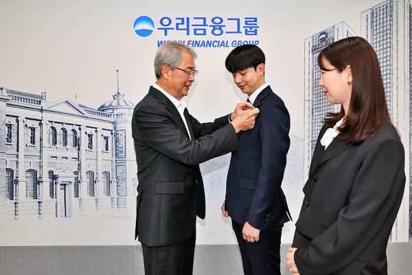 ▲우리금융그룹 임종룡 회장이 그룹의 새 가족이 된 동양생명·ABL생명 직원에게 디지털 선도의 의미가 담긴 새로운 그룹 보조휘장을 달아주고 있다.